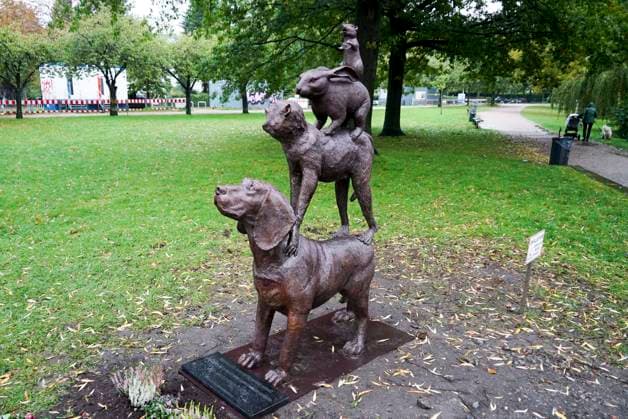Hamburg - Alstervorland 15.10.21 Neues Denkmal für den Tierschutz durch unbekannten Kuenstler aufgestellt Mahnendes Guerilla-Kunstwerk gegen Tierversuche auf Alsterwiese - Stadtmusikanten-Bildnis eines unbekannten Künstlers – Ausdrucksstarke Figuren stimmen nachdenklich Spaziergänger am Ufer der Hamburger Außenalster haben einen neuen Hingucker bekommen. Denn auf einer Alsterwiese steht nun ein mahnendes Guerilla-Kunstwerk gegen Tierversuche, das nicht nur durch seine ausdrucksstarken Figuren zum Nachdenken anregt. Den Bremer Stadtmusikanten nachempfunden trägt ein Hund einen Affen, dieser einen Hasen und der eine Ratte auf seinen Schultern. Die hochwertige Plastik sieht aus wie aus Bronze gearbeitet. Ein schweres Fundament sorgt für en