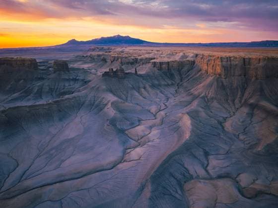 Creative Highlights World Aerial View of Rugged Desert Badlands at Sunrise with Vibrant Sky Hanksville, Utah, United States CR_EVVA250214-1639828-01