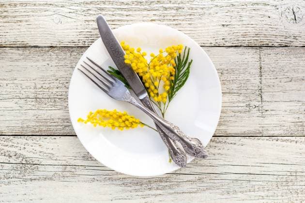 Festive table setting plate with fork and knife and mimosa flower decoration on white wooden background with copy space Festive table setting plate with fork and knife and mimosa flower decoration on white wooden background with copy space. Spring dinner, holiday, Easter concept Copyright: xZoonar.com FedorovaxDariax 22849120