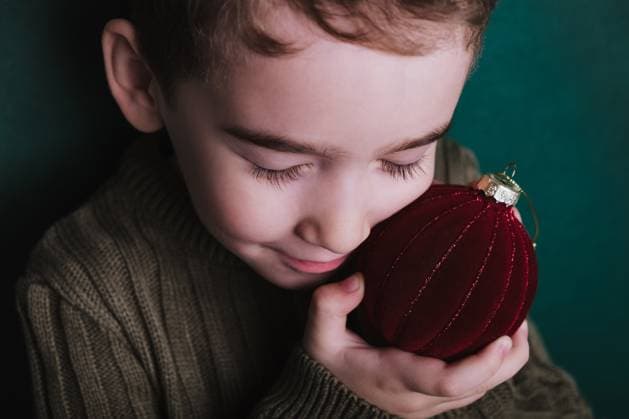 Creative Highlights Symbolfotos A young boy with closed eyes gently embraces a red velvety Christmas ornament, expressing serene holiday warmth. Model Released HelenaNechaeva_ID18087_543973_004 Copyright: xx
