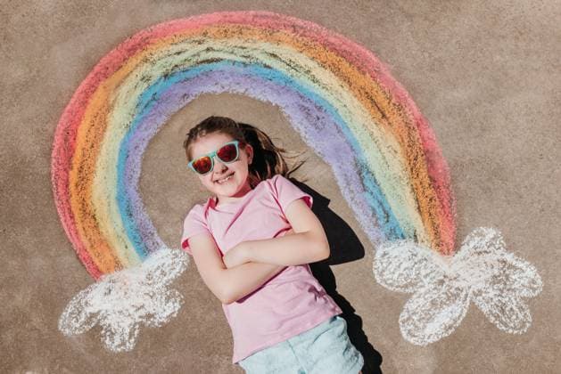 Creative Highlights Symbolfotos Girl with colorful clothes lays on concrete by chalk rainbow Sioux Falls, South Dakota, United States CR_ASWE250218-1647497-01 ,model released, Symbolfoto