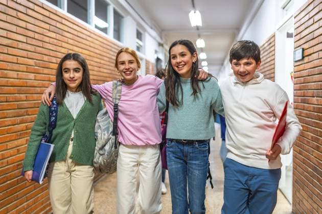 Gruppe von fröhlichen Schülern, die gemeinsam im Schulflur spazieren gehen und die Arme umeinander legen Group of cheerful students walking together in school hallway with arms around each other Copyright: imageBROKER UnaixHuizi ibxuhu12678532.jpg ,model released, Symbolfoto ,property released