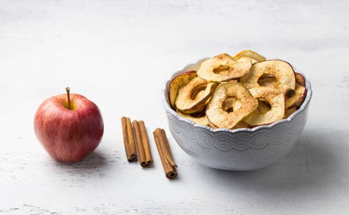 Hausgemachte getrocknete Äpfel mit Zimt, Apfelchips in einer Schüssel mit Zimtstangen auf einem hellgrauen Hintergrund. Leckerer gesunder Snack Homemade dried apples with cinnamon, apple chips in a bowl with cinnamon sticks on a light gray background. Delicious healthy snack. Copyright: xZoonar.com OlgaxLepeshkinax 22905058