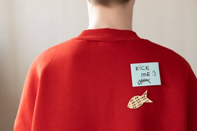 Boy in red hoodie with a paper attached with tape to his back with the handwriting text kick me. Fools day joke. , 50986364.jpg, all fools day, joke, poisson davrille, concept, red, humor, french, adult, april, april fools day, back, background, blue, celebrate, celebration, closeup, colorful, comical, conceptual, day, event, festive, first, fish, fish-shaped, fool, fools, fools day, fun, funny, game, happy, holiday, homemade, joy, leisure, lifestyle, message, paper, party, person, playful, positive, prank, preschooler, silly, spring, tease, text, young RECORD DATE NOT STATED