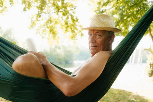 Creative Highlights Symbolfotos Senior man wearing straw hat relaxing in hammock at lakeshore model released, Symbolfoto property released, GUSF01787