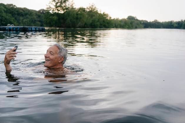 Senior man using cell phone in a lake model released, Symbolfoto, GUSF01807