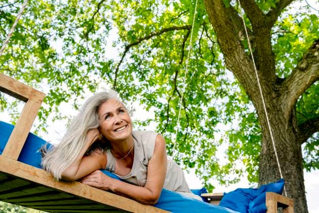 Creative Highlights Symbolfotos Smiling woman with long grey hair lying on a bed in garden model released, Symbolfoto property released, PESF01367
