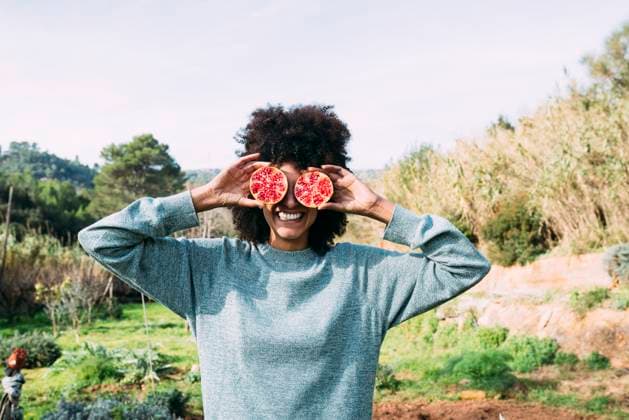 Creative Highlights Symbolfotos Woman standing in the countryside, covering eyes with halved pomegranates model released, Symbolfoto property released, GEMF02826