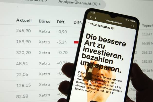 Auf einem Smartphone wurde die Website vom Neobroker Trade Republic aufgerufen. Dahinter wurden auf einem Laptop die Liste der handelbaren Aktien an der Deutschen Börse aufgerufen. Symbolbild Symbolfoto. Schnelsen Hamburg *** The website of the neobroker Trade Republic was called up on a smartphone Behind it, the list of tradable shares on the German stock exchange was called up on a laptop Symbol image Symbol photo Schnelsen Hamburg