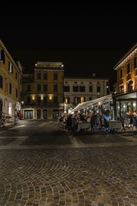 Abendliches Essen auf einem Platz umgeben von beleuchteten historischen Gebäuden, Nachtfotos mit langer Belichtungszeit aufgenommen in Peschiera del Garda, Italien Verona Evening dining in a plaza surrounded by illuminated historic buildings, night photos taken at long exposure time taken in Peschiera del Garda, Italy Verona Copyright: imageBROKER dfeens ibxkrm12746314.jpg