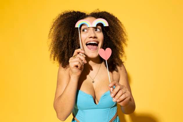 Creative Highlights Symbolfotos Playful woman with rainbow and heart prop standing against yellow background model released, Symbolfoto, MIKF00602