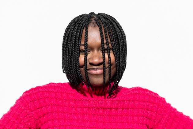 Creative Highlights Symbolfotos Woman with braids in a pink sweater smiling at the camera against a white wall model released, Symbolfoto, LMCF02088