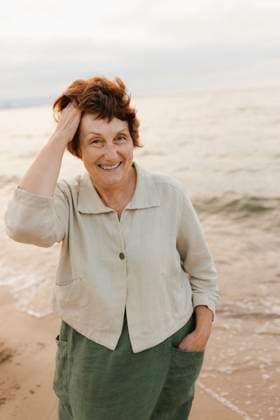 Creative Highlights Symbolfotos Smiling senior woman with hand in hair by sea at beach model released, Symbolfoto, VIVF01502