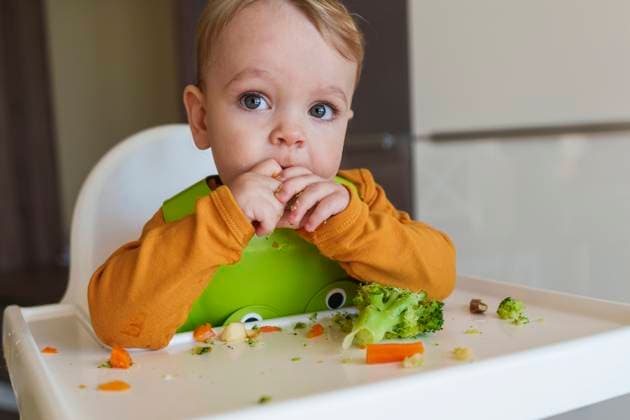 Creative Highlights Symbolfotos Toddler eating broccoli sitting on high chair at home model released, Symbolfoto property released, AAZF02161