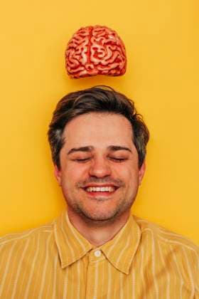 Smiling man with brain above head on yellow background model released, Symbolfoto, VSNF02934