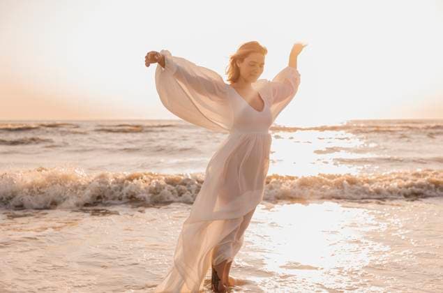 Creative Highlights Symbolfotos Woman in a flowing white dress standing in ocean waves at sunset Amsterdam, North Holland, Netherlands CR_RTBZ250220-1658363-01 ,model released, Symbolfoto