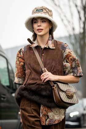 Street Style at Milan Fashion Week 2025 - Gucci in Milan, Italy on 25 February 2025 Street Style: A guest wears light brown Gucci monogram sherpa lined Gucci bucket hat, gold earrings, light gray dark orange bear pattern short sleeve oversized shirt, dark brown suede zipped vest, shiny dark brown Gucci monogram leather bag outside of the Gucci fashion show during the Milan Fashion Week Womenswear Fall Winter 2025 2026 in Milan, Italy on 25 February 2025., Credit:Stefano Costantino TTL Avalon Milan, Italy  Copyright: xStefanoxCostantinoxTTLx xAvalonx 0968952523
