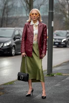 Street Style at Milan Fashion Week 2025 - Gucci in Milan, Italy on 25 February 2025 Street Style: A guest wears bright orange sunglasses, gold hoop earrings, white sheer mesh buttoned up yellow floral detail shirt, silver chain necklace, shiny burgundy bordeaux leather jacket, shiny high waisted midi skirt outside of the Gucci fashion show during the Milan Fashion Week Womenswear Fall Winter 2025 2026 in Milan, Italy on 25 February 2025., Credit:Stefano Costantino TTL Avalon Milan, Italy  Copyright: xStefanoxCostantinoxTTLx xAvalonx 0968952654