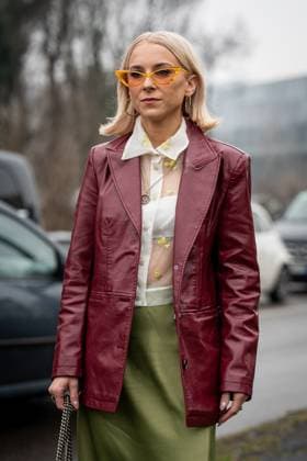 Street Style at Milan Fashion Week 2025 - Gucci in Milan, Italy on 25 February 2025 Street Style: A guest wears bright orange sunglasses, gold hoop earrings, white sheer mesh buttoned up yellow floral detail shirt, silver chain necklace, shiny burgundy bordeaux leather jacket, shiny high waisted midi skirt outside of the Gucci fashion show during the Milan Fashion Week Womenswear Fall Winter 2025 2026 in Milan, Italy on 25 February 2025., Credit:Stefano Costantino TTL Avalon Milan, Italy  Copyright: xStefanoxCostantinoxTTLx xAvalonx 0968952679