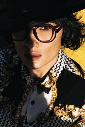 Creative Highlights Symbolfotos A stylish woman in a black hat and glasses wears a patterned shirt with gold details. The sunlight casts an artistic shadow on her face, highlighting her fashion-forward look. Model Released FranRuiz_ID26430_762513_001 Copyright: xFranxRuizx RECORD DATE NOT STATED