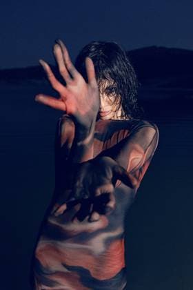 Creative Highlights Symbolfotos A woman poses dramatically under low light, with vibrant shadows and colors casting patterns on her body, evoking mystery and artistic expression Model Released FranRuiz_ID26430_762525_013 Copyright: xFranxRuizx RECORD DATE NOT STATED