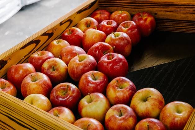 A rustic wooden box filled with fresh red apples is neatly arranged, creating a pleasing visual display. The natural tones of the wood complement the vibrant colors of the apples, enhancing their organic appeal. Model Released VictorTorres_ID26852_774921_141 Copyright: xVictorxTorresx