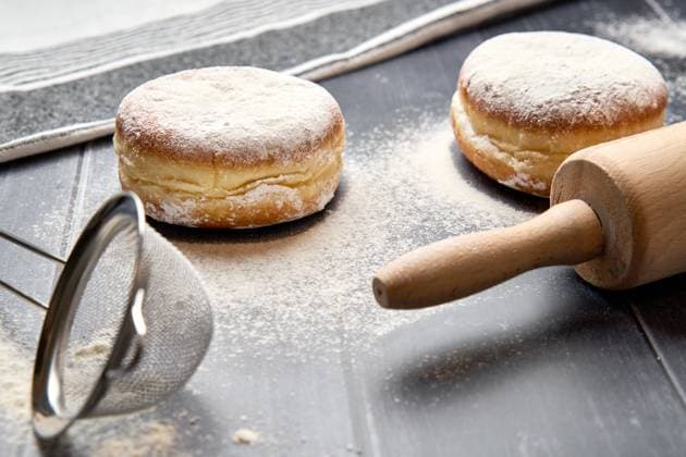Germany - February 28, 2025: Freshly baked Berliner with a layer of powdered sugar on a floured work surface *** Frisch gebackener Berliner mit einer Schicht Puderzucker auf einer bemehlten Arbeitsfläche