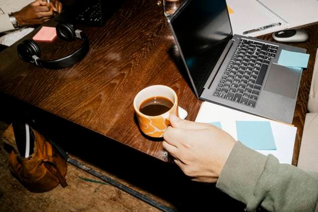Creative Highlights Symbolfotos High angle view of male entrepreneur holding coffee cup near laptop on desk at office Sweden, Stockholm, model released, property released Copyright: xMaskotx , MA116406 MA116406