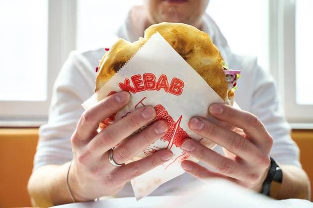 IMAGO Creative, Food, Fast Food, Döner Karlsruhe, Baden-Württemberg, Germany - March 4, 2025: Man holding a doner kebab in a printed doner kebab wrapper. Fast food dish in a restaurant or snack bar. Typical street food with meat, salad and sauce *** Mann hält einen Döner Kebab in einer bedruckten Dönerverpackung. Fastfoodgericht im Restaurant oder Imbiss. Typisches Streetfood mit Fleisch, Salat und Sauce