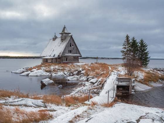 Verschneite Winterlandschaft mit authentischem Filmhaus am Ufer im russischen Dorf Rabocheostrovsk. Snowy winter landscape with authentic cinematic house on the shore in the Russian village Rabocheostrovsk. A wooden chapel built for the filming of the film. Copyright: xZoonar.com StanislavxSablinx 22974645