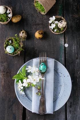 Colorful Easter quail eggs Table setting decor colorful Easter quail eggs with spring cherry flowers, moss in garden pots, empty plates, cutlery over old wood background. Dark rustic style. Top view with copy space. Copyright: xZoonar.com NatashaxBreenx 22981064