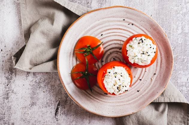 Close up of fresh tomatoes filled with cottage cheese and herbs on a plate on the table top view Close up of fresh tomatoes filled with cottage cheese and herbs on a plate on the table top view Copyright: xZoonar.com ElenaxRuix 22966695