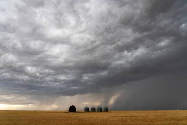 Dramatic supercell storm clouds forming over a farm in the plains Ominous supercell storm clouds gathering over a farm with grain silos and a barn in the vast plains Copyright: xZoonar.com mark.duffyx 23014354