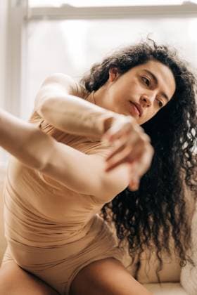 Creative Highlights Symbolfotos Woman stretching gracefully with a serene expression near a window Somerville, Massachusetts, United States CR_FKNH250305A-1660222-01 ,model released, Symbolfoto