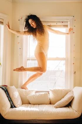 Creative Highlights Symbolfotos Woman balancing elegantly near a sunlit window in a graceful pose Somerville, Massachusetts, United States CR_FKNH250305A-1660326-01 ,model released, Symbolfoto