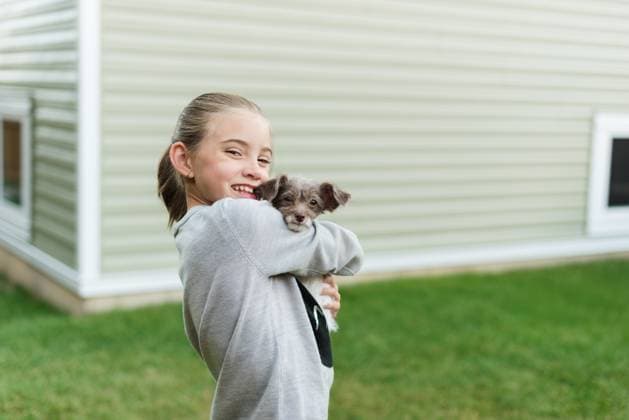 Creative Highlights Symbolfotos Young girl smiling while she holds her new puppy and family pet Canada, British Columbia, Sparwood R_PKZL250307-1673501-01 ,model released, Symbolfoto