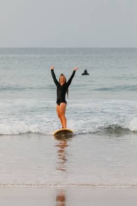 Creative Highlights Symbolfotos A female surfer rides a small wave and raises her hands in excit Peniche, Leiria District, Portugal CR_MGUJ250310C-1674903-01 ,model released, Symbolfoto