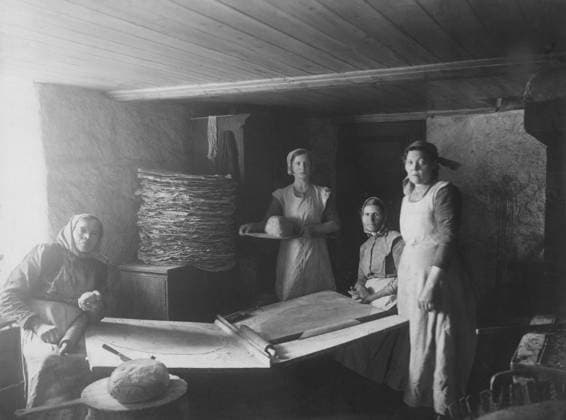 Brotbacken 1917. Interieur eines Raums mit Frauen, die Brot backen, nachdem sie bereits einen großen Stapel Brot gebacken haben. Der spezielle Backtisch und die traditionellen Backwerkzeuge wie Nudelholz sind zu sehen. Aufnahme an der Südwestküste Schwedens, Bohuslän, in einer ländlichen Umgebung 1917 Baking bread 1917. Interior of a room with women baking bread, having already baked a large pile of bread. The speical baking table and the traditional baking tools like rolling pin is visible. Picture taken on the south-west coast of Sweden, Bohuslän in a rural setting 1917 Copyright: imageBROKER Sjoberg ibljsj12886205.jpg