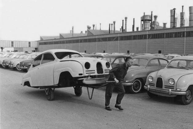 Automobilbau in den 1950er Jahren. Die Saab Autofabrik in Schweden mit ihrer Produktionslinie. Ein merkwürdiges Bild eines Arbeiters, der das Fahrgestell eines Saab Autos auf einem Wagen hinter sich herzieht. Es handelt sich um das Modell Saab 96, das zwischen 1960 und 1963 hergestellt wurde. Schweden 1961 Car manufacturing in the 1950s. The Saab car factory in Sweden with it s line of production. An odd picture of a worker dragging the chassi of a Saab motor car behind him on a carriage. The model is Saab 96 that was manufactured between 1960-1963. Sweden 1961 Copyright: imageBROKER Sjoberg ibljsj12896494.jpg