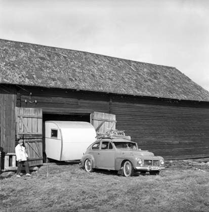 Wohnwagen in den 1950er Jahren. Eine Familie hat ihren Wohnwagen im Winter in der Scheune geparkt, und es ist an der Zeit, den Wohnwagen für den Sommerurlaub herauszuholen. Das Auto ist ein Volvo PV. Conard Nr. 3722 Caravan in the 1950s. A family has parked their caravan in the barn during the winter and it s time to take it out to use the caravan for the summer holiday. The car is a Volvo PV. Conard ref 3722 Copyright: imageBROKER Sjoberg ibljsj12885520.jpg