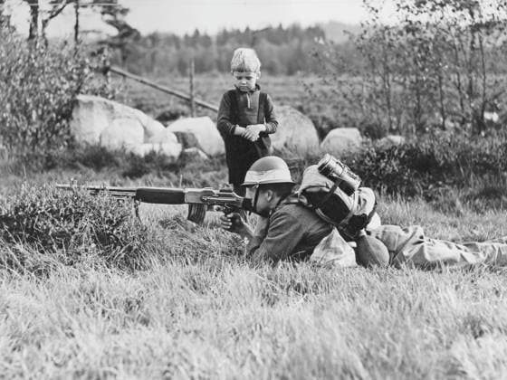 Der Zweite Weltkrieg steht bevor. Schweden rüstet die Verteidigung und übt im Herbst 1938 in Smaland. Ein Soldat liegt feldmäßig auf dem Feld in der smaländischen Natur und zielt mit seinem Gewehr. Ein kleiner Junge steht an der Seite und schaut staunend zu. 18. September 1938 World War II is coming. Sweden equips the defense and exercises in the fall of 1938 in Smaland. A soldier lies field-like in the field in the Smaland nature and aims with his rifle. A little boy stands to the side and looks on in wonder. 18 September 1938 Copyright: imageBROKER Sjoberg ibljsj12891857.jpg