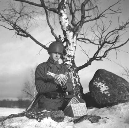 Schwedische Armee während des Zweiten Weltkriegs. Man sieht einen Soldaten, der eine Taube in den Händen hält. Kriegstauben wurden während des Zweiten Weltkriegs vom schwedischen Militär eingesetzt. Die Tauben überbrachten Nachrichten von einem Ort zum anderen, oft ein Stück Papier in einem kleinen Metallbehälter, der am Bein der Taube befestigt war. Die Brieftauben wurden von einer Spezialeinheit des schwedischen Militärs betreut und ausgebildet. Brieftauben spielten eine wichtige Rolle bei der Invasion in der Normandie, da Funkgeräte nicht verwendet werden konnten, weil man befürchtete, daß wichtige Informationen vom Feind abgefangen werden könnten. Schweden, Dezember 1940. Kristoffersson ref 184 3 Swedish army during WW2. A soldier i Copyright: imageBROKER Sjoberg ibljsj12892002.jpg