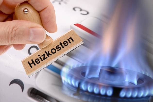 Nebenkosten und Heizkosten Eine Hand hält einen Holzstempel mit der Aufschrift Heizkosten vor eine brennende Gasflamme und ein Heizungsthermostat - Symbolbild - FOTOMONTAGE *** Service charges and heating costs A hand holds a wooden stamp with the inscription Heizkosten (heating costs) in front of a burning gas flame and a heating thermostat Symbol image FOTOMONTAGE