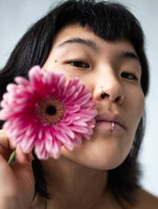 Creative Highlights Symbolfotos Close-up portrait of an Asian woman with short hair, holding a pink flower near her face. The image captures the serene expression and natural beauty of the subject. Model Released Gaorstudio_ID26044_751624_008 Copyright: xGaorstudiox RECORD DATE NOT STATED