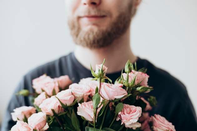 Creative Highlights Symbolfotos A bearded young man holds a bouquet of delicate pink roses close to his chest. The gentle focus highlights the blossoms, symbolizing a romantic and heartfelt gesture. Model Released HannaYakimenko_ID27183_781577_008 Copyright: xHannaxYakimenkox