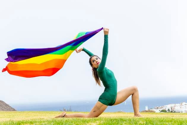 Creative Highlights Symbolfotos A woman in a green outfit gracefully poses with a vibrant rainbow flag, symbolizing LGBTQIA+ pride and unity. The outdoor setting enhances the scene s lively energy. Model Released JuanAizpuru_ID26732_771911_015 Copyright: xJuanxAizpurux RECORD DATE NOT STATED