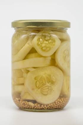 A glass jar filled with sliced pickled cucumbers immersed in vinegar, showcasing mustard seeds at the bottom. Perfect for illustrating food preservation or homemade pickling. Model Released LauraZamora_ID26925_776983_017 Copyright: xLauraxZamorax RECORD DATE NOT STATED