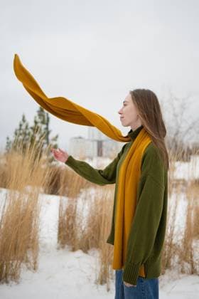 Creative Highlights Symbolfotos MR_ID27001_20082_AlenaZhdanova.jpg A woman in a green sweater stands in a snowy park, her mustard scarf caught in the breeze. Tall grass and distant trees provide a serene winter backdrop. Model Released LiliyaSolopova_ID27001_779263_004 Copyright: xLiliyaxSolopovax RECORD DATE NOT STATED