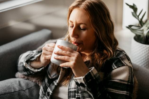 A woman in her 40s enjoys a warm drink on the couch Boise, Idaho, United States R_PHZD250312-1676904-01 ,model released, Symbolfoto