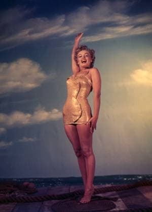 RECORD DATE NOT STATED Marilyn Monroe Circa 1956 in Los Angeles, California: American actress and Hollywood icon MARILYN MONROE smiling while posing barefoot and wearing a gold colored outfit and reaching for the sky in this classic portrait. Copyright: x1956,entertainment,color,film,Hollywood,MarilynxMonroe,movies,vintage,classic,classicxHollywood,1950 s,vintagexHollywood,GoldenxAgexofxHollywood,x